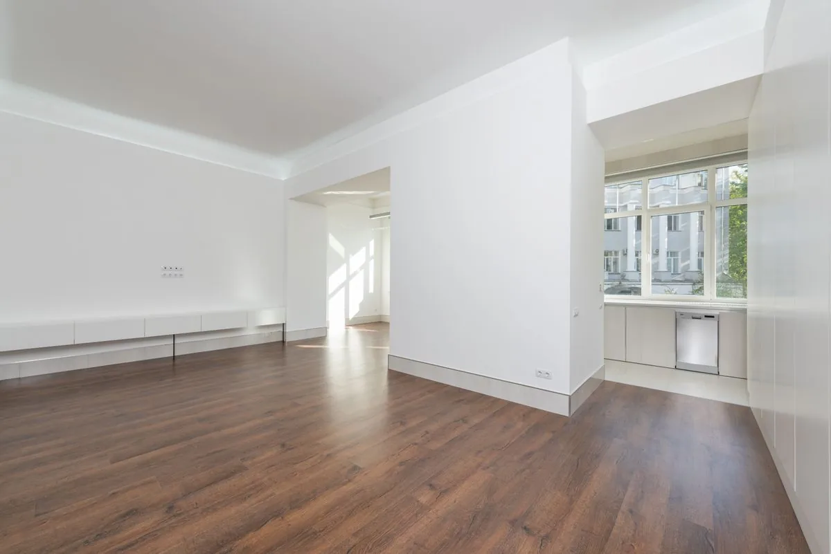 Leere, helle Wohnung mit weißen Wänden und Holzboden