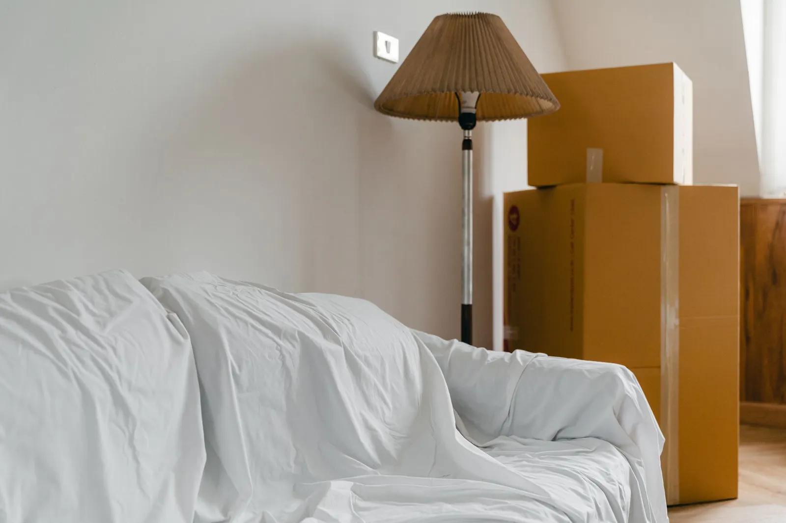 Wohnzimmer mit abgedecktem Sofa und Umzugskartons